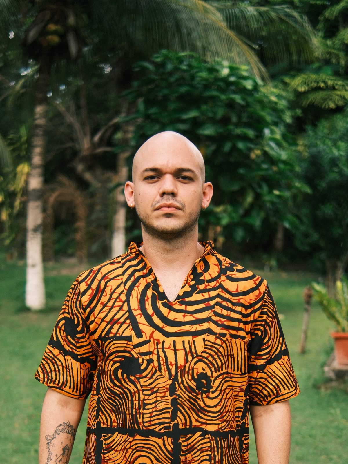 Retrato de Junior Quintela em vestes africanas, em meio a coqueiral